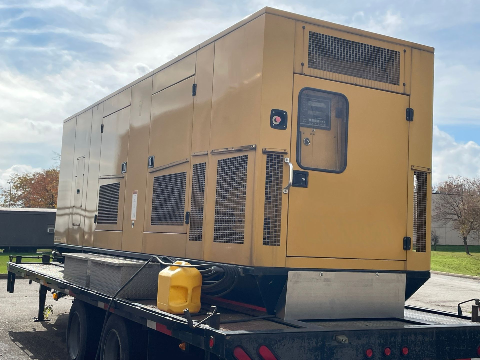 A large yellow generator is sitting on top of a flatbed truck.