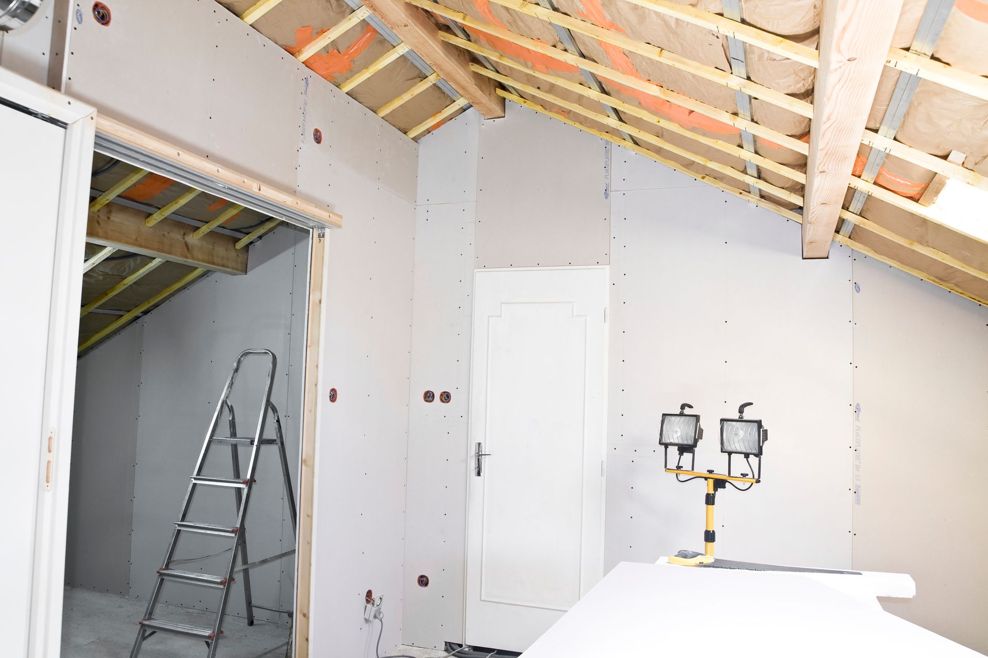 A room under construction with a ladder and two lights.