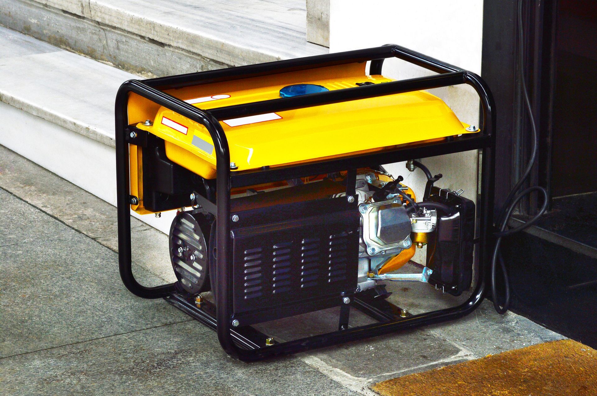 A yellow generator is sitting on the sidewalk next to a door.