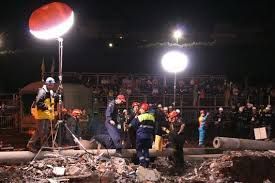 A group of people are working on a construction site at night.