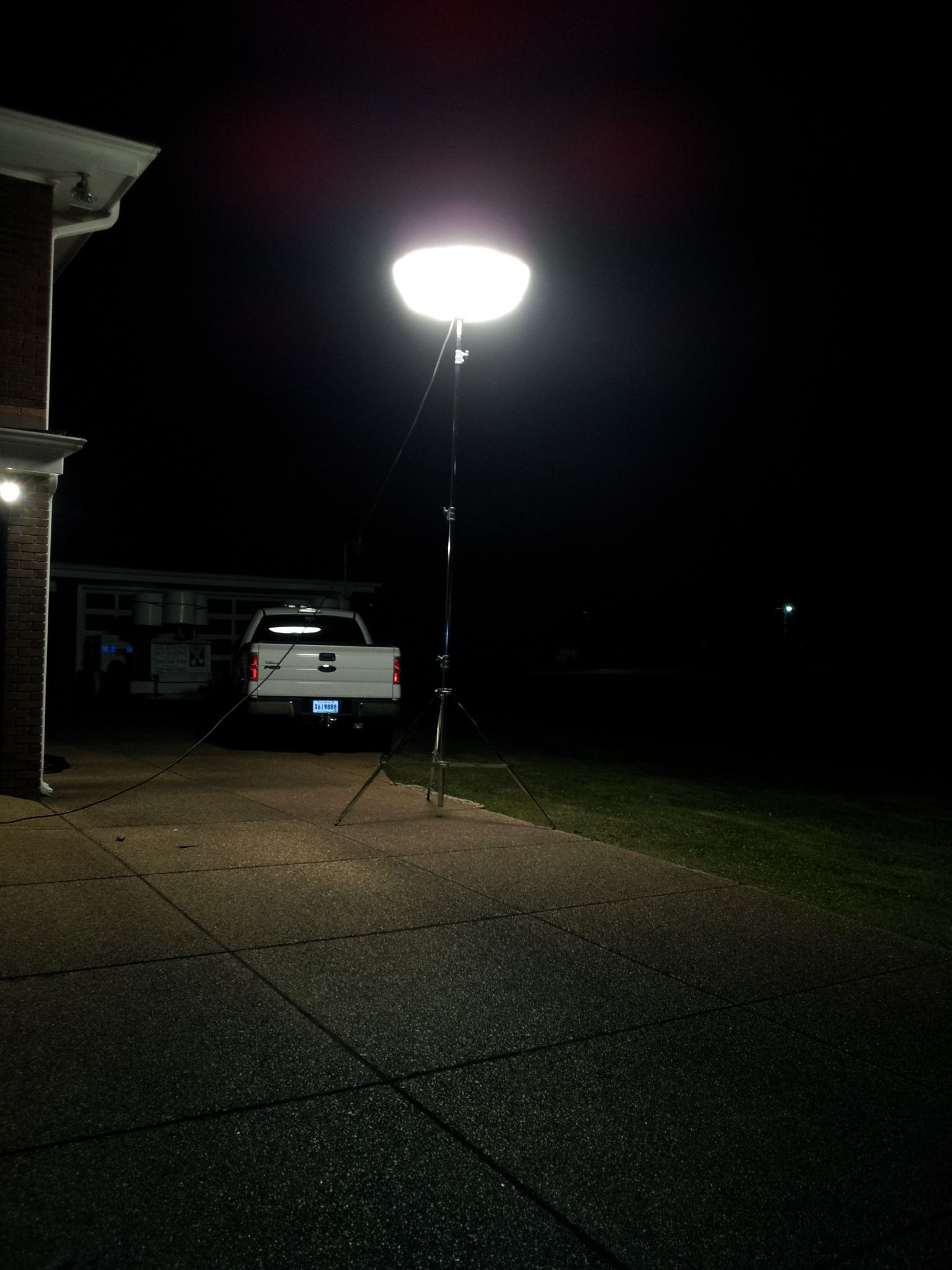 A white truck is parked in front of a house at night.