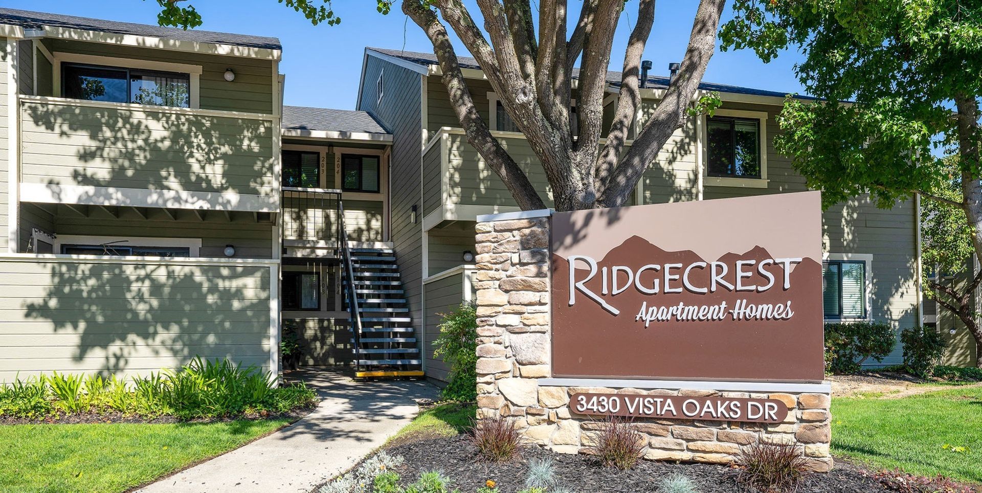 Exterior view of Ridgecrest Apartment Homes entrance with sign and landscaping.