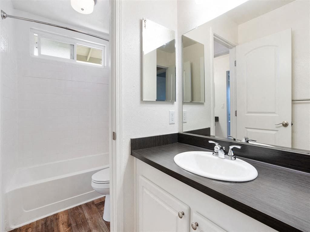 Bathroom with white sink, dark countertop, large mirror, and a bathtub/shower.