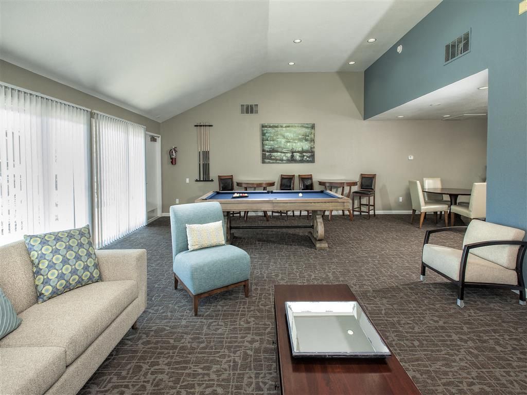 Indoor community lounge with a pool table, couches, chairs, and large windows.