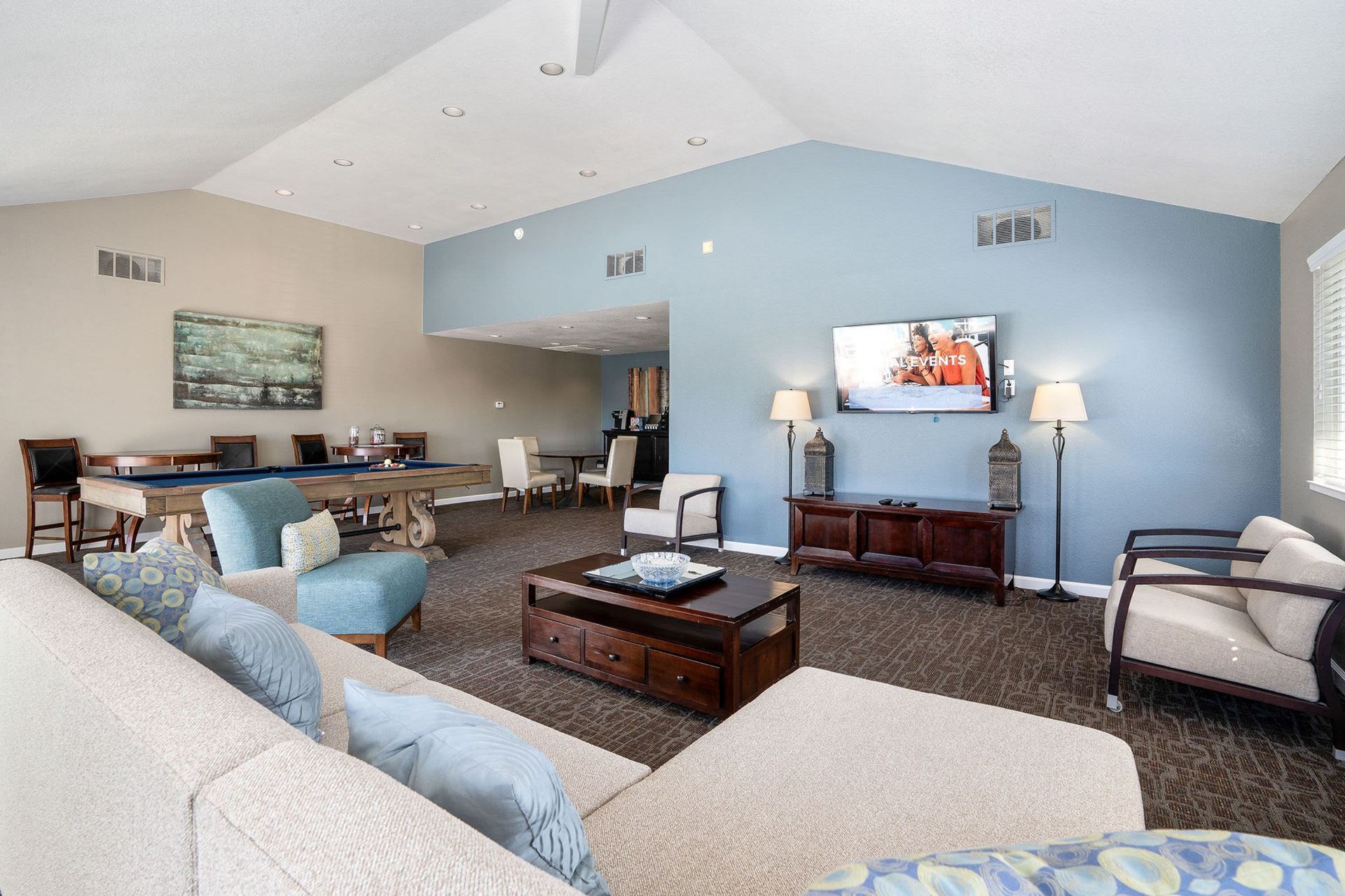 Spacious lounge with pool table, TV, couches, and armchairs. Blue and brown color scheme.