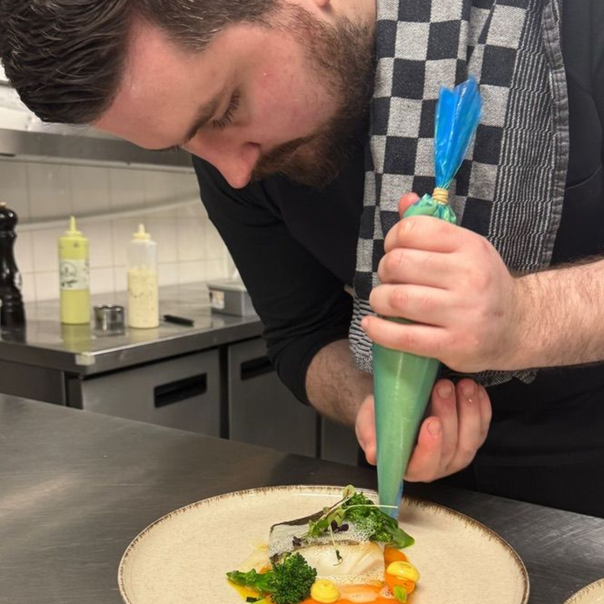 Een vrouw draagt ​​een zwart shirt en een ketting en lacht naar de camera.