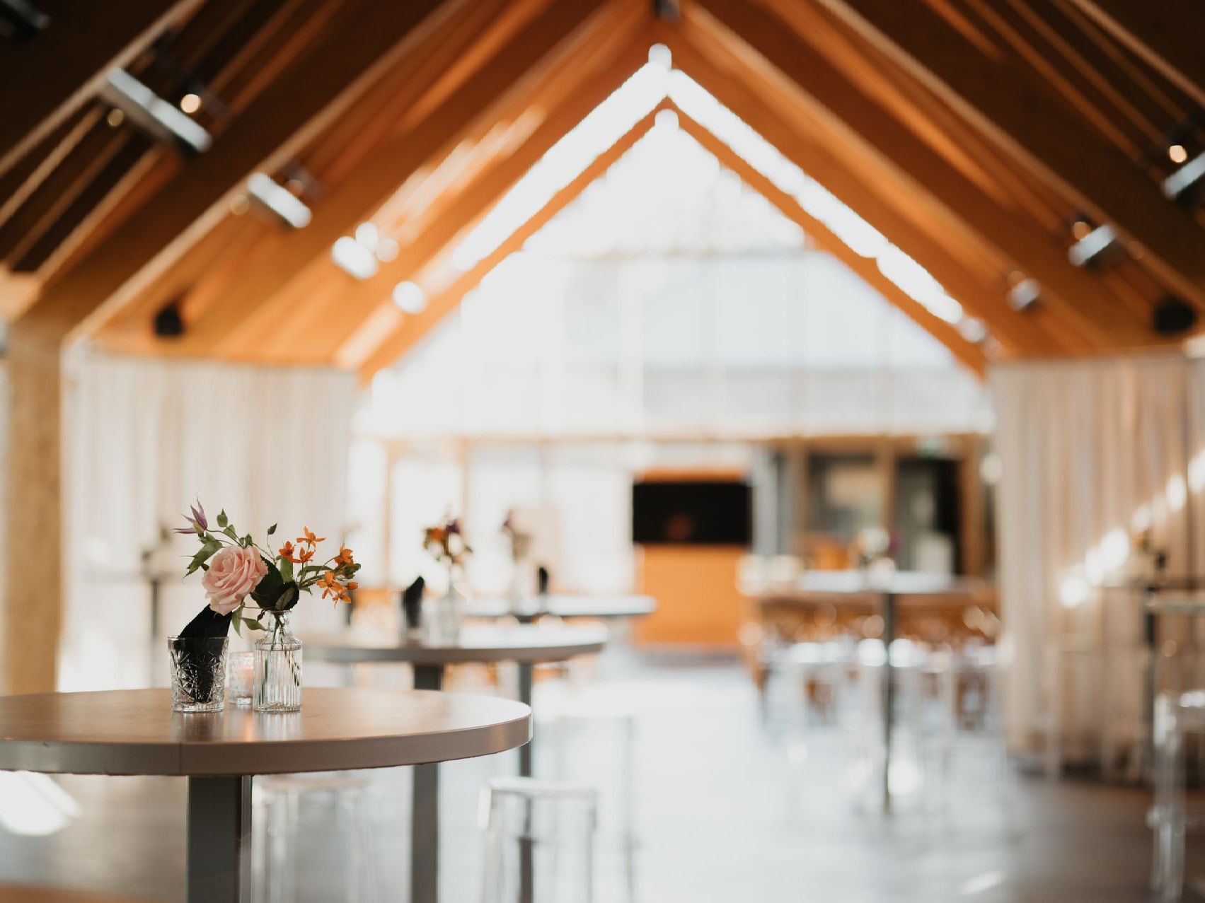 Een grote kamer met tafels en stoelen en een houten plafond