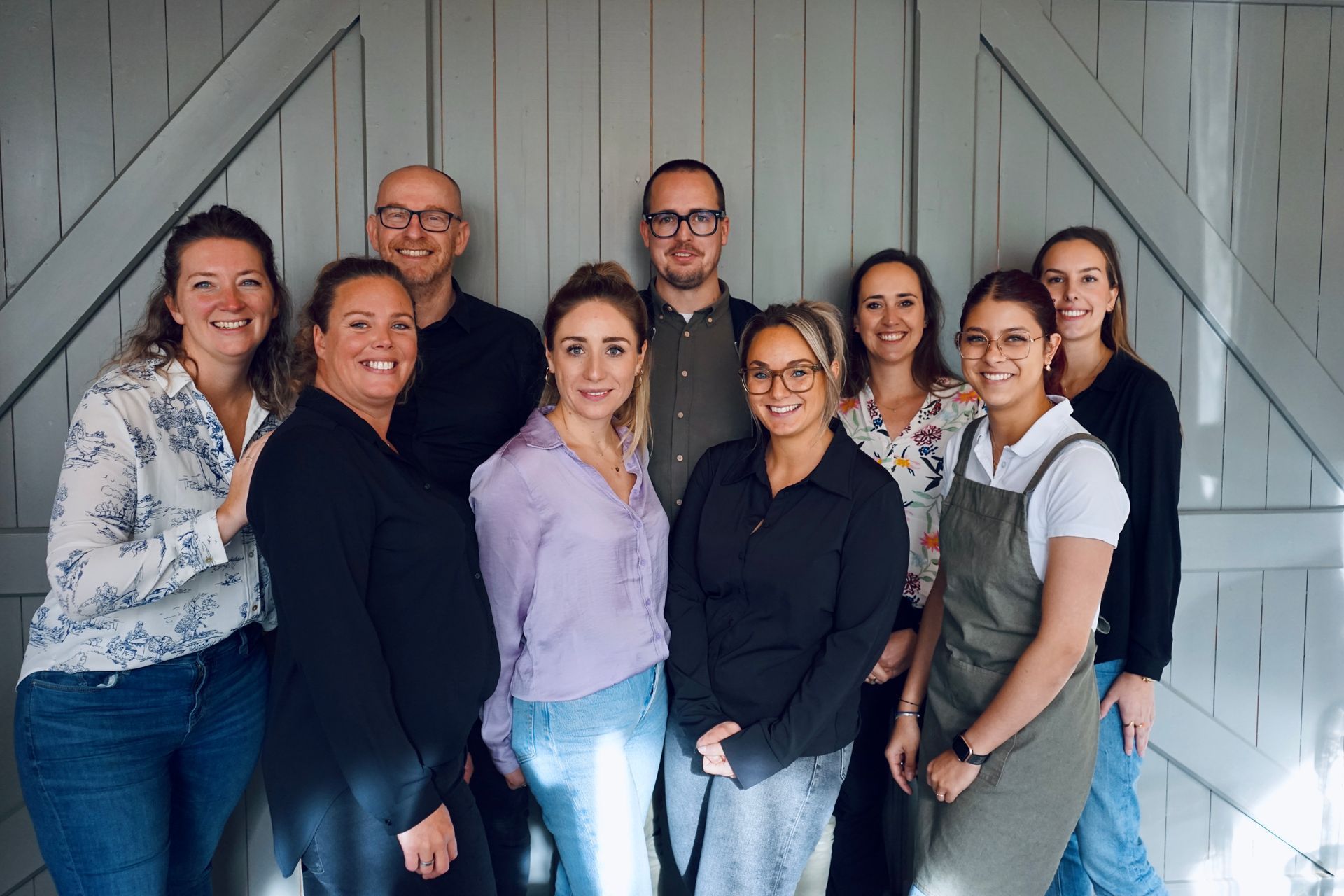 Een groep vrouwen poseert voor een foto voor een bakstenen muur.