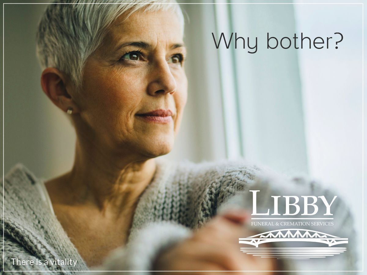 An older woman is looking out of a window.