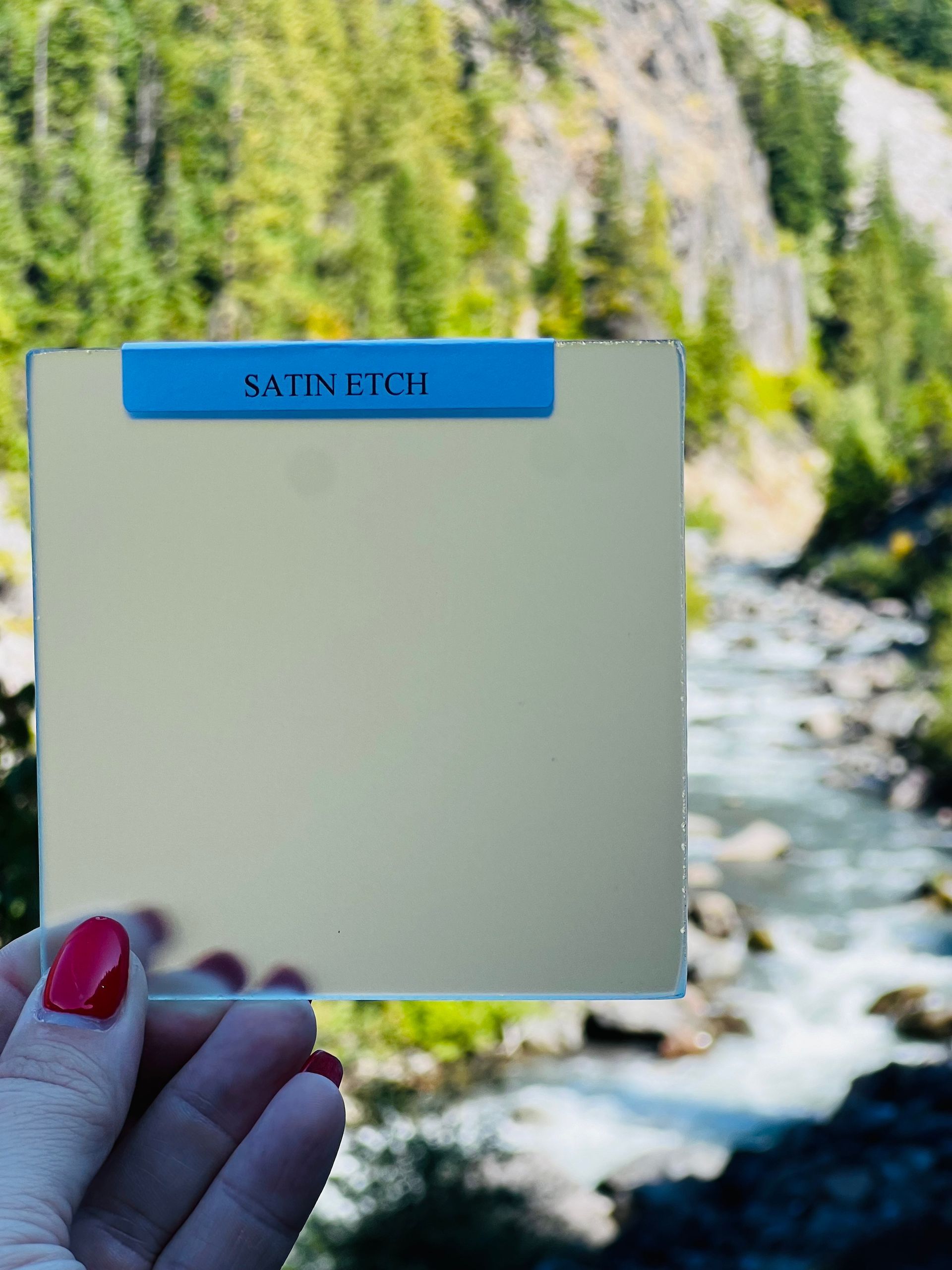 A person is holding a piece of paper in front of a river.