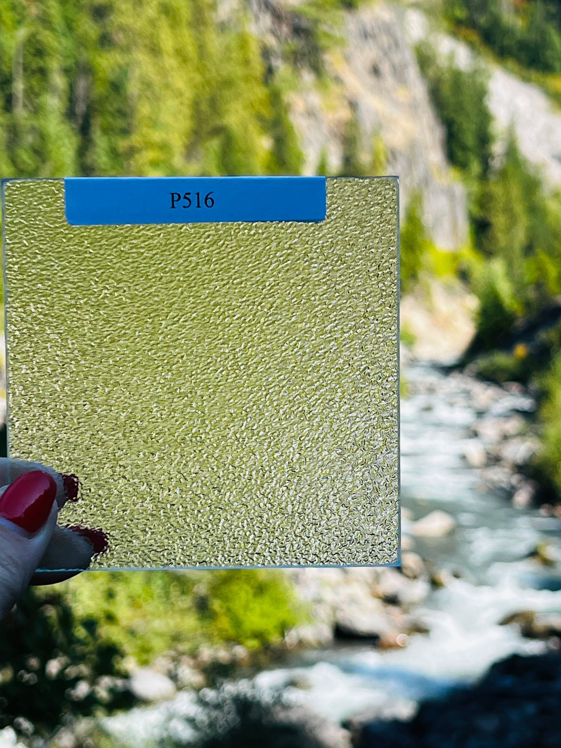A person is holding a piece of glass in front of a river.