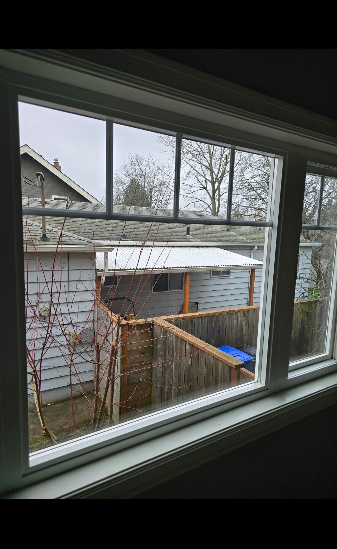 A window with a view of a house and a fence.