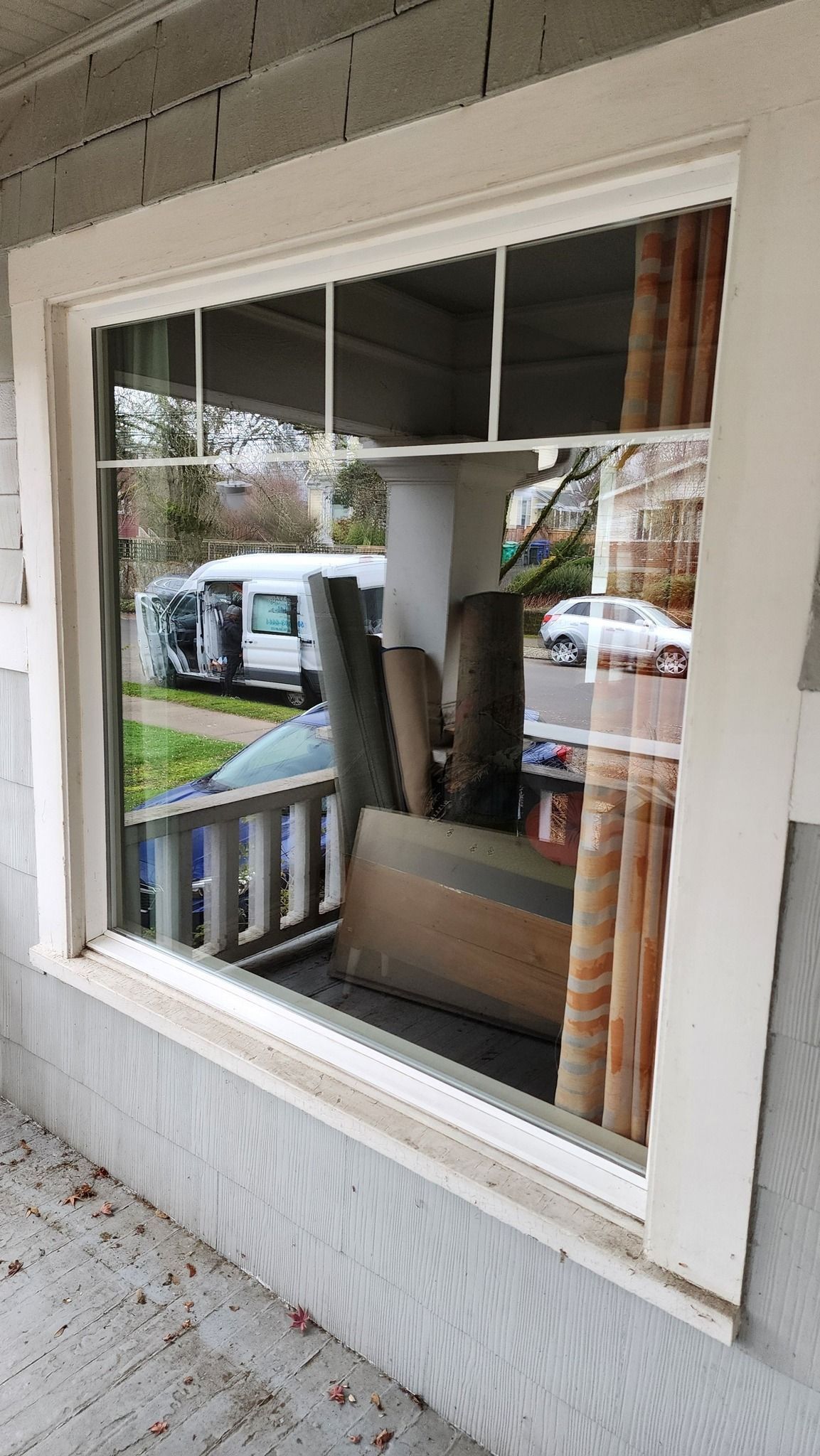 A window on the side of a house with a reflection of a car in it.