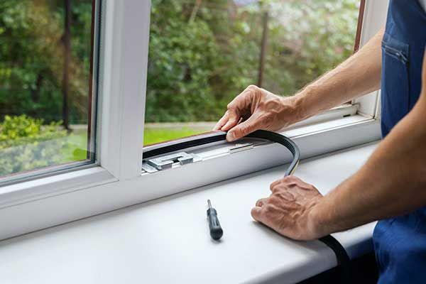 A man is installing a window seal on a window sill.