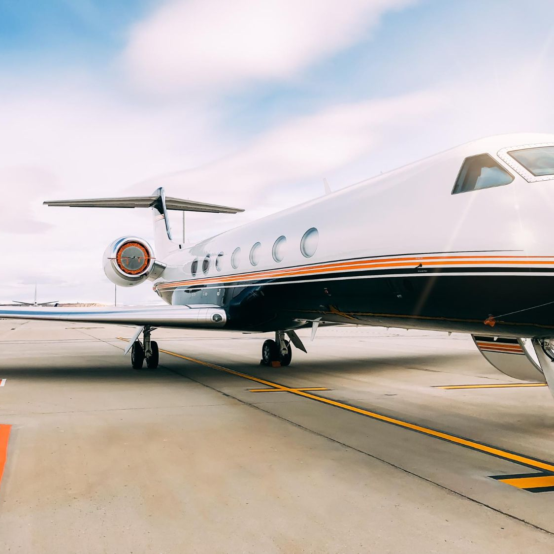 Two pilots walk toward a white airplane in a hangar with a blue floor.