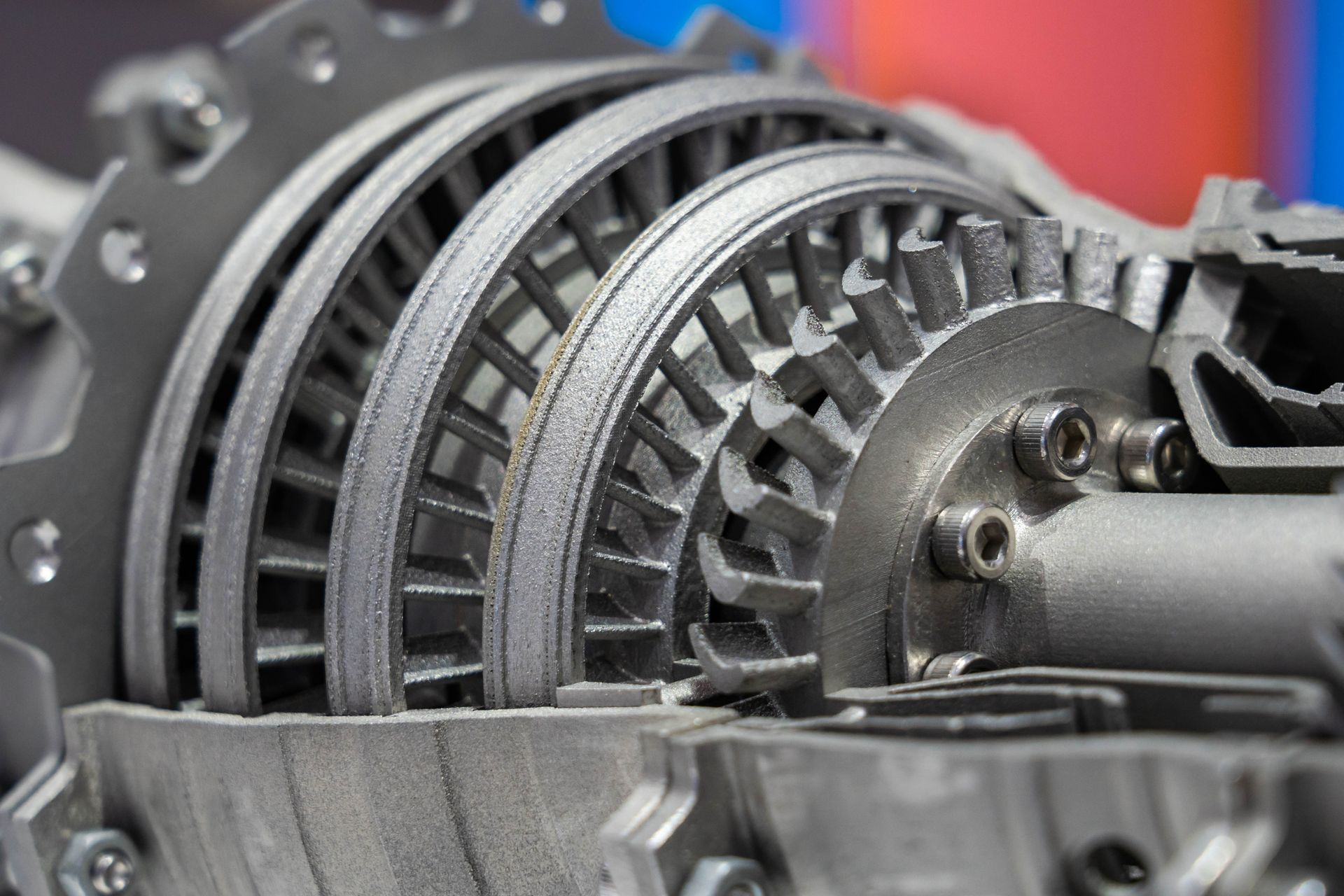 Mechanic in blue jumpsuit and gloves selects a wrench from a red toolbox near orange equipment.