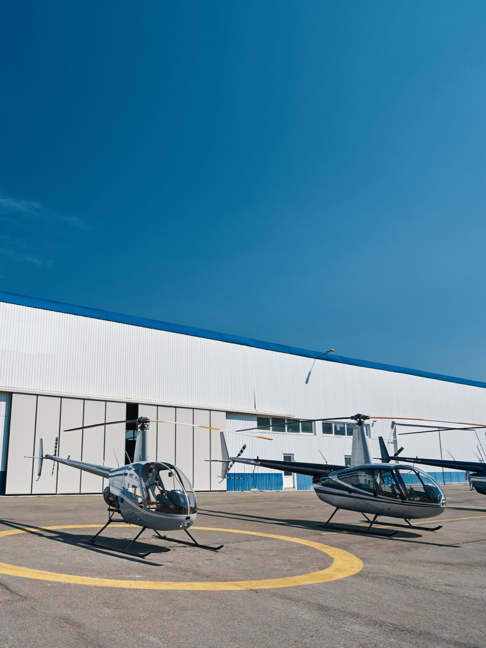 Aircraft assembly hangar with two partially built airplanes. One red, one green. Tools and scaffolding visible.