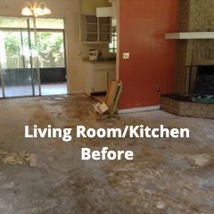 A room undergoing renovation with exposed subflooring, a brick fireplace, a partial kitchen, and a glass patio door.