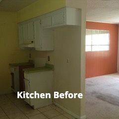 A dimly lit kitchen with pale walls, white cabinets, and green countertops, next to a room with terracotta-colored walls.