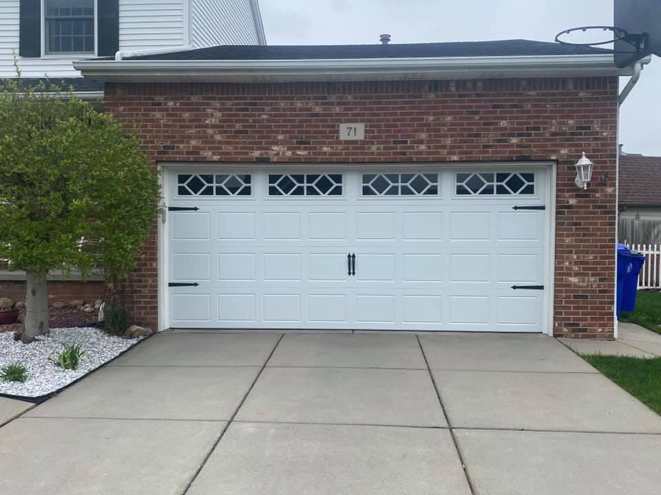 White garage door on a brick house with black hardware, address 