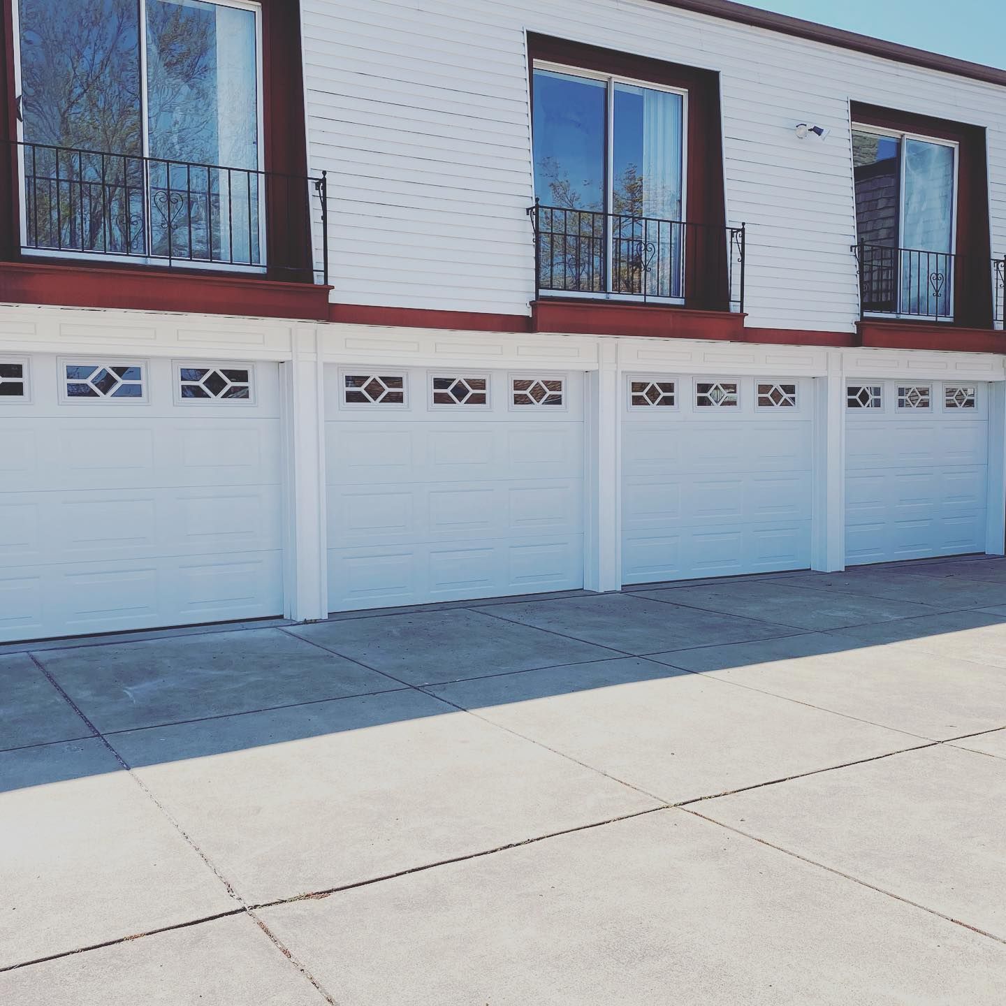 White garages under a white building with windows and balconies, on a sunny day.