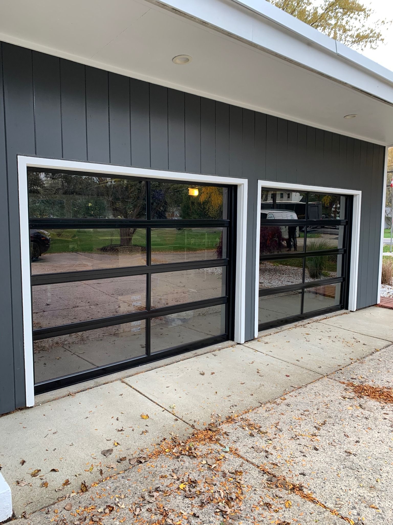 Two modern garage doors with clear glass panels and black frames.