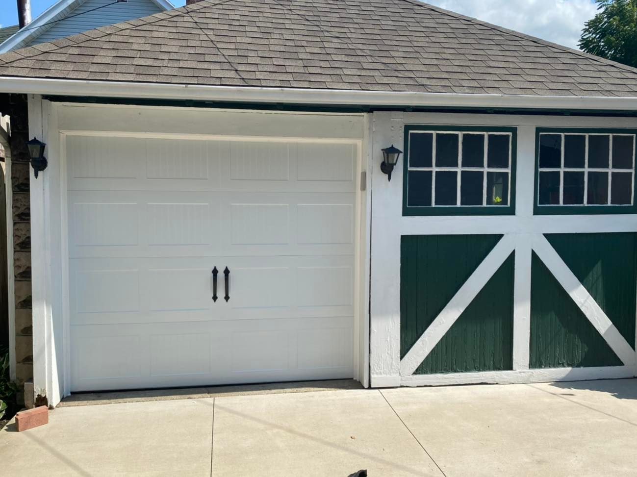 White garage door next to green door with white diagonal trim and small windows.