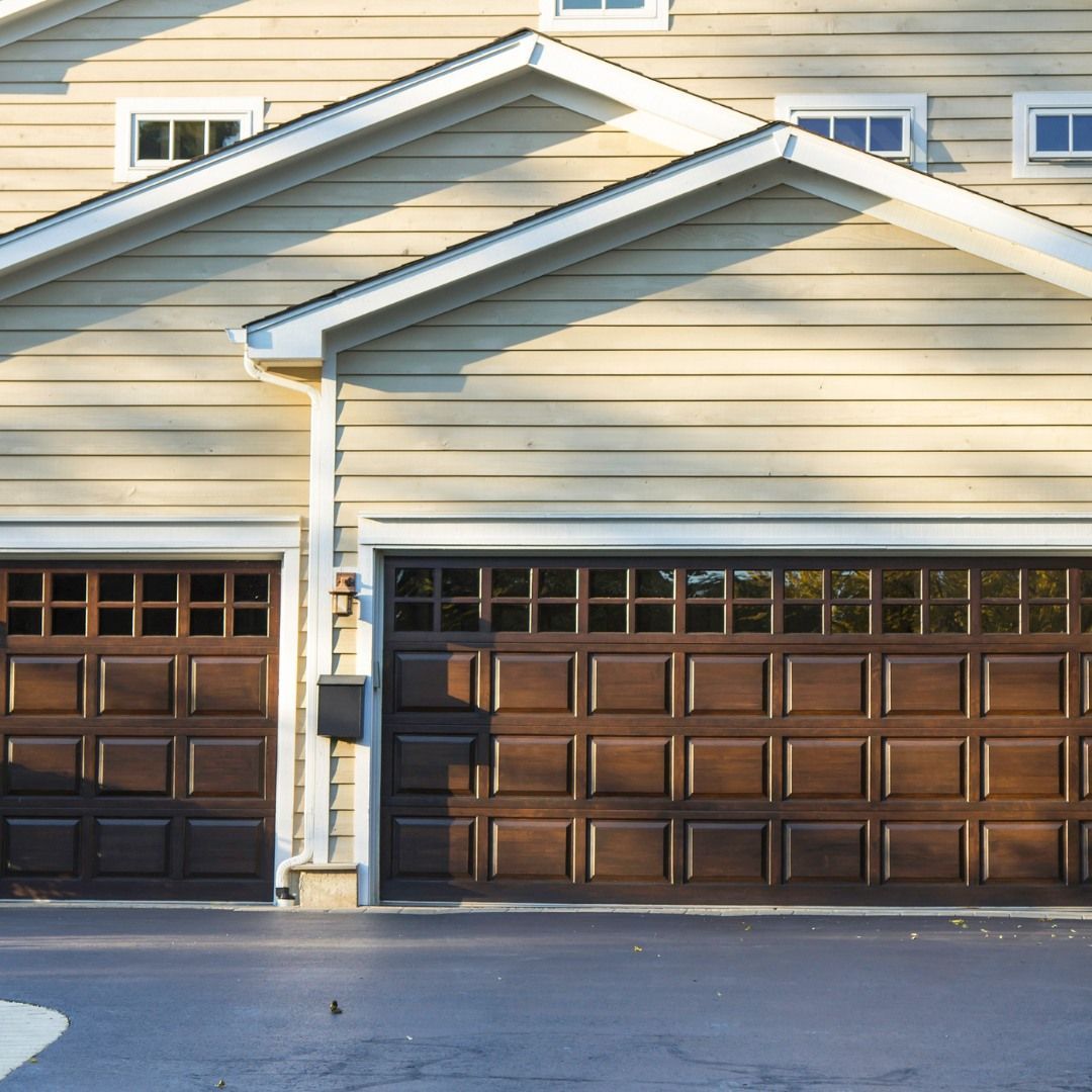 Tan house with brown garage doors and a dark driveway.