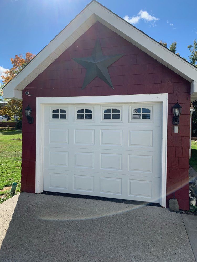 Red garage with white trim and door; green metal star above.