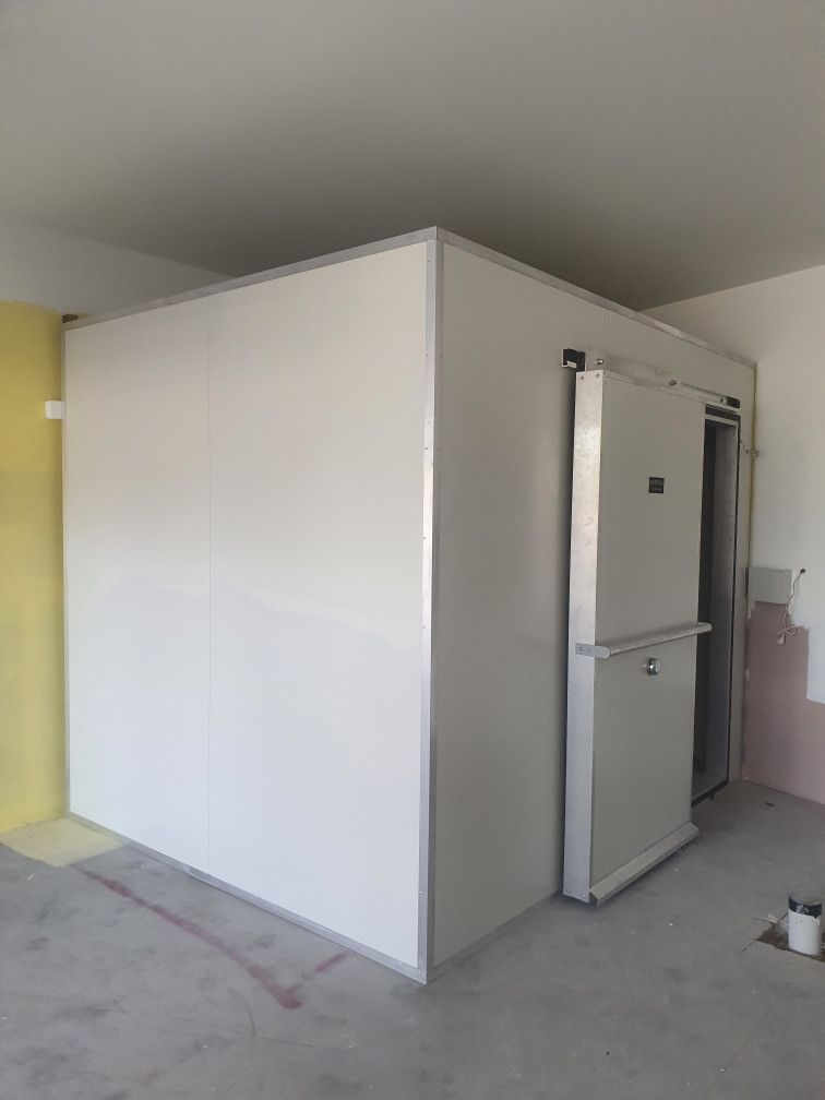 White walk-in cooler with sliding door in a room. Walls are white and tan.— Cool Tropics Air Conditioning & Refrigeration in Mourilyan Harbour, QLD