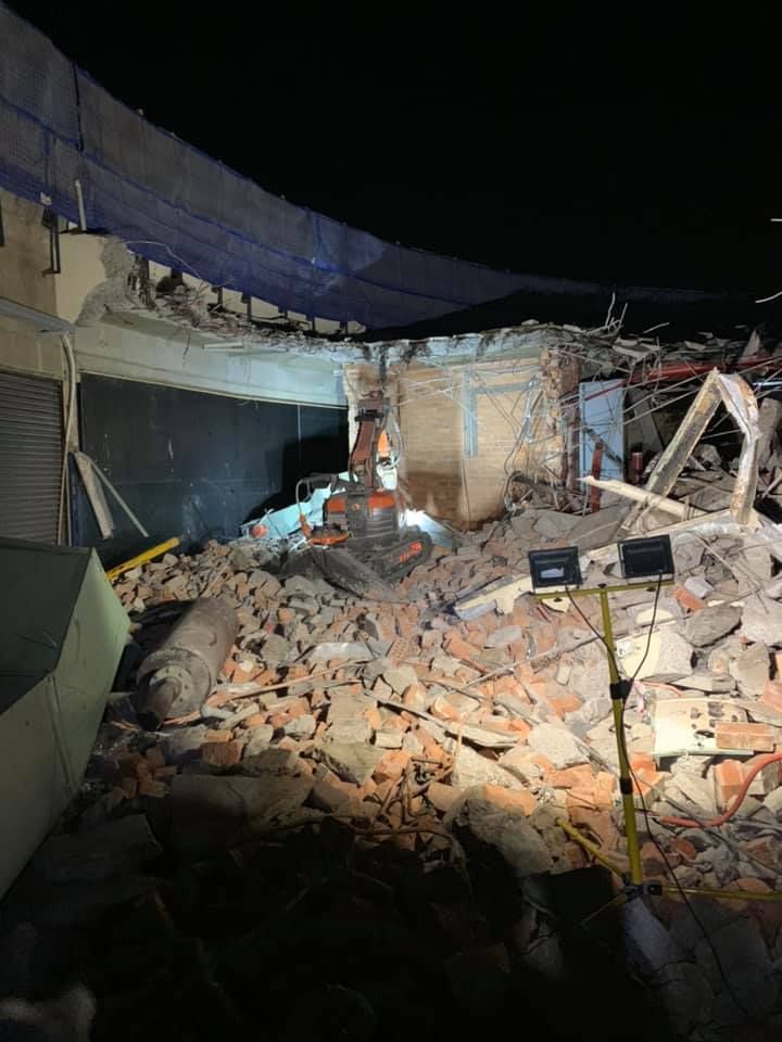 A brick building is being demolished at night with a bulldozer. — Newcastle Cut N Drill Pty Ltd In Boolaroo, NSW