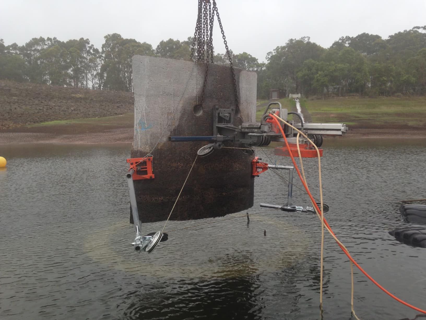 A large piece of concrete is being lifted into the water by a crane. — Newcastle Cut N Drill Pty Ltd In Boolaroo, NSW