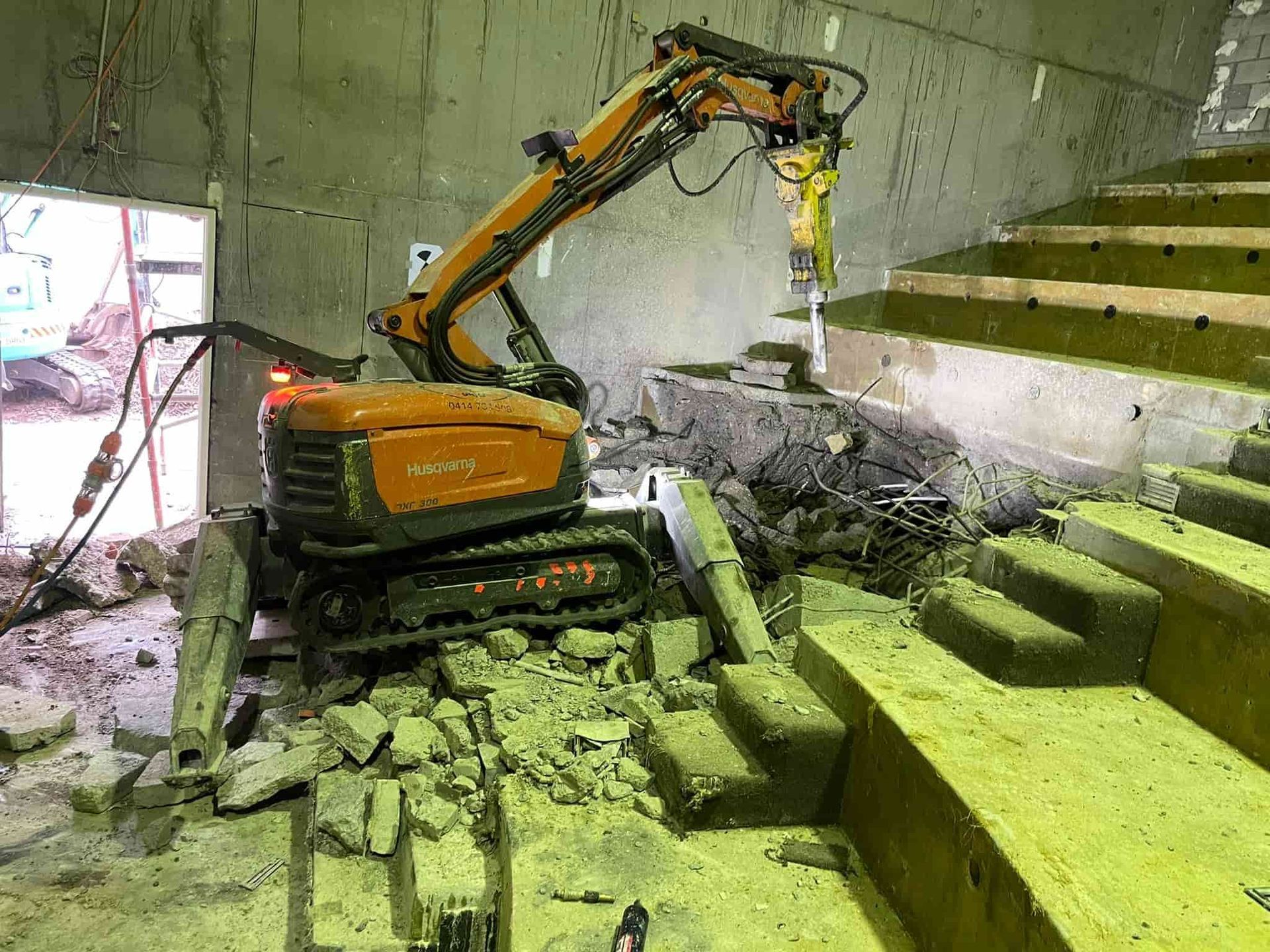 A robot is breaking concrete in a building next to stairs. — Newcastle Cut N Drill Pty Ltd In Boolaroo, NSW