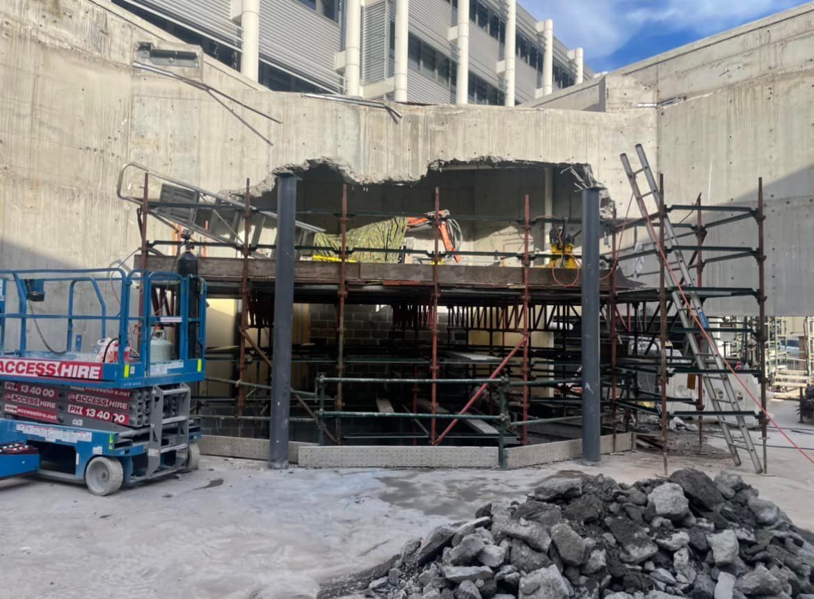 A construction site with a crane and scaffolding in front of a building under construction. — Newcastle Cut N Drill Pty Ltd In Boolaroo, NSW