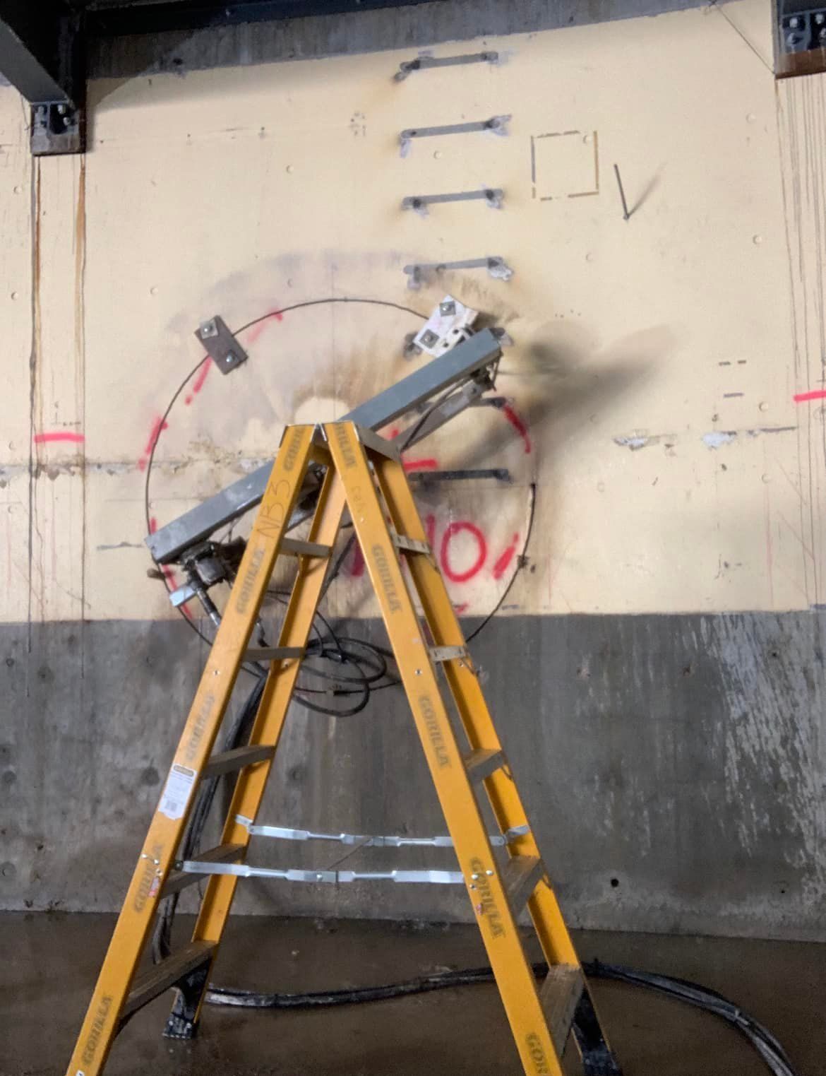 A yellow ladder is sitting in front of a wall with the number 10 written on it — Newcastle Cut N Drill Pty Ltd In Boolaroo, NSW