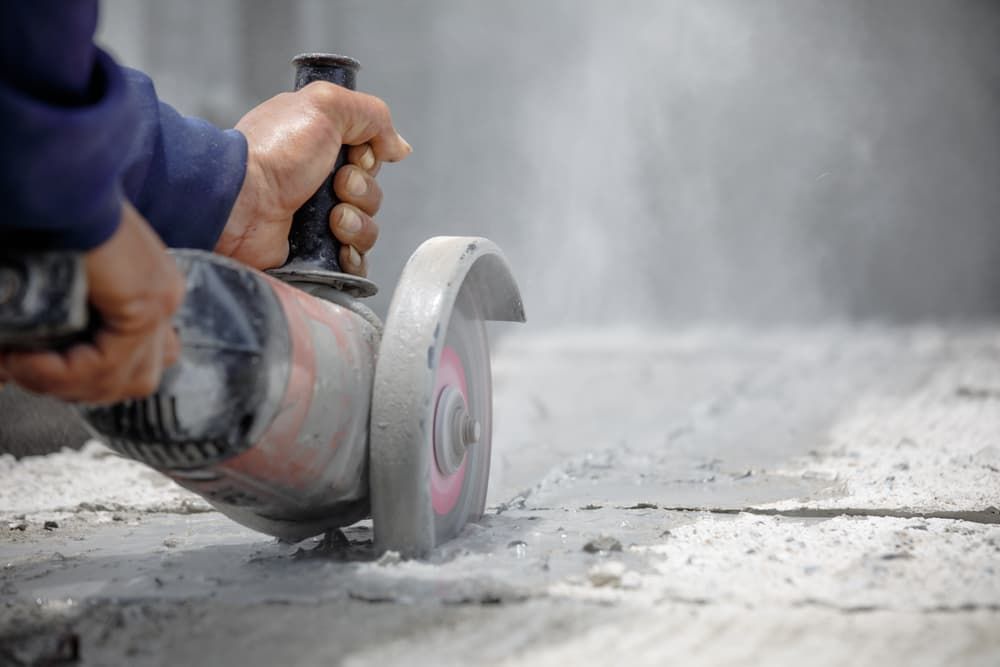 A man is cutting a piece of concrete with a grinder. — Newcastle Cut N Drill Pty Ltd In Boolaroo, NSW