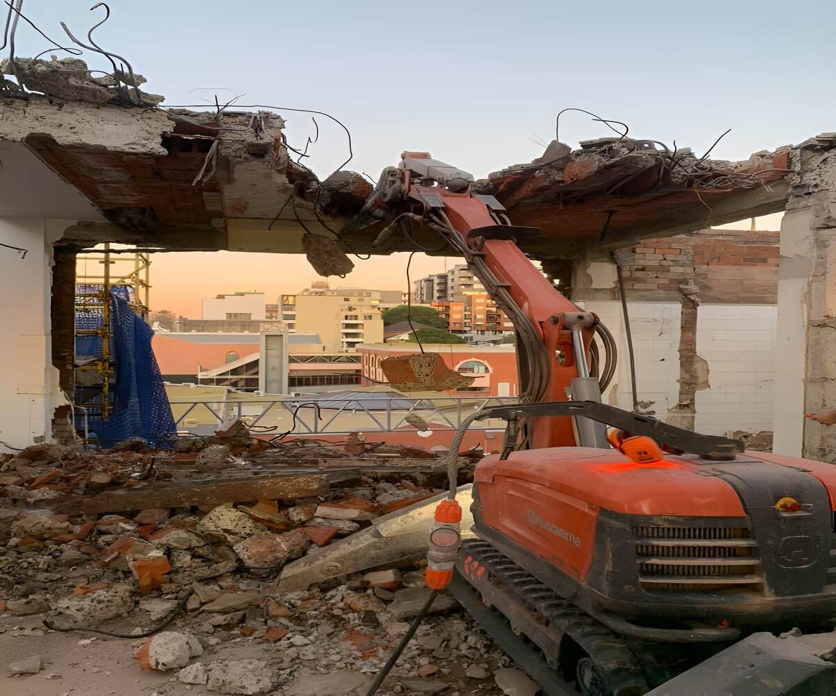 A Bulldozer Is Demolishing A Building With A City In The Background — Newcastle Cut N Drill Pty Ltd In Boolaroo, NSW