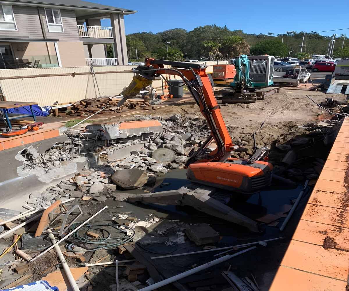 A Large Orange Excavator Is Sitting On Top Of A Pile Of Rocks — Newcastle Cut N Drill Pty Ltd In Boolaroo, NSW