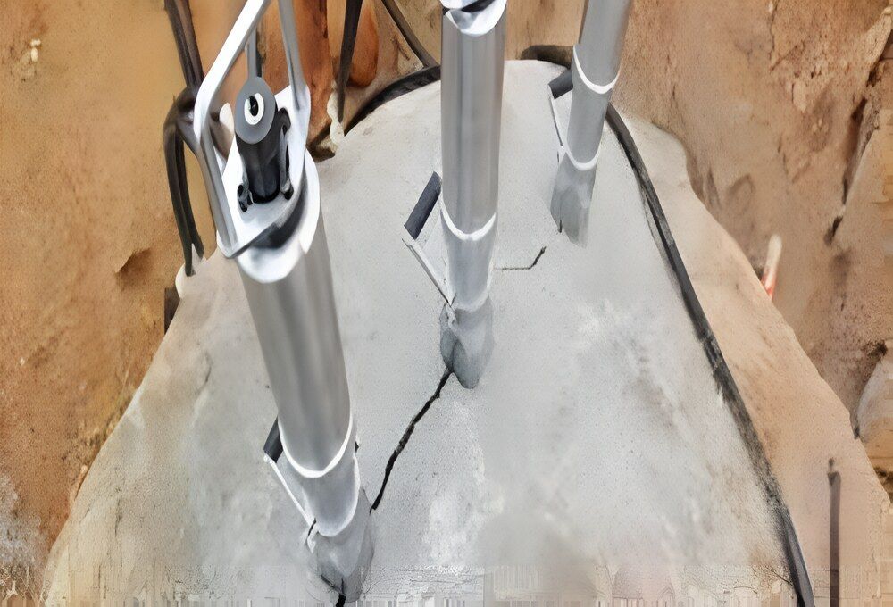 A Group Of Metal Pipes Are Sitting On Top Of A Large Rock — Newcastle Cut N Drill Pty Ltd In Boolaroo, NSW