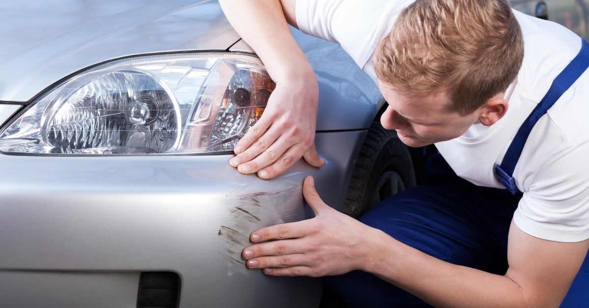 Closeup of a professional taking a look at a series of scratches near the driver’s side headlight.