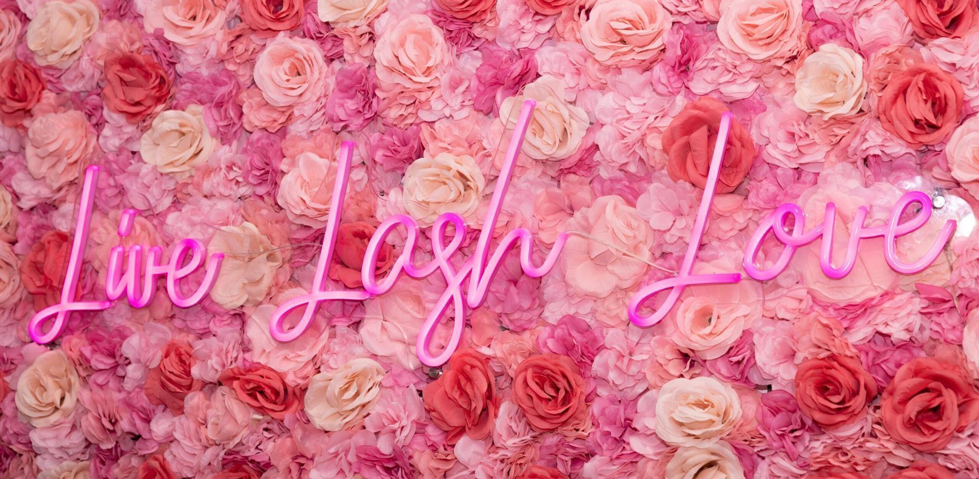 A neon sign that says `` live laugh love '' is surrounded by pink roses.