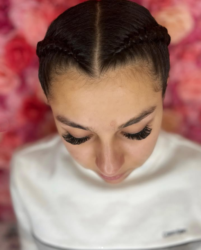 A close up of a woman 's face with braids and long eyelashes.