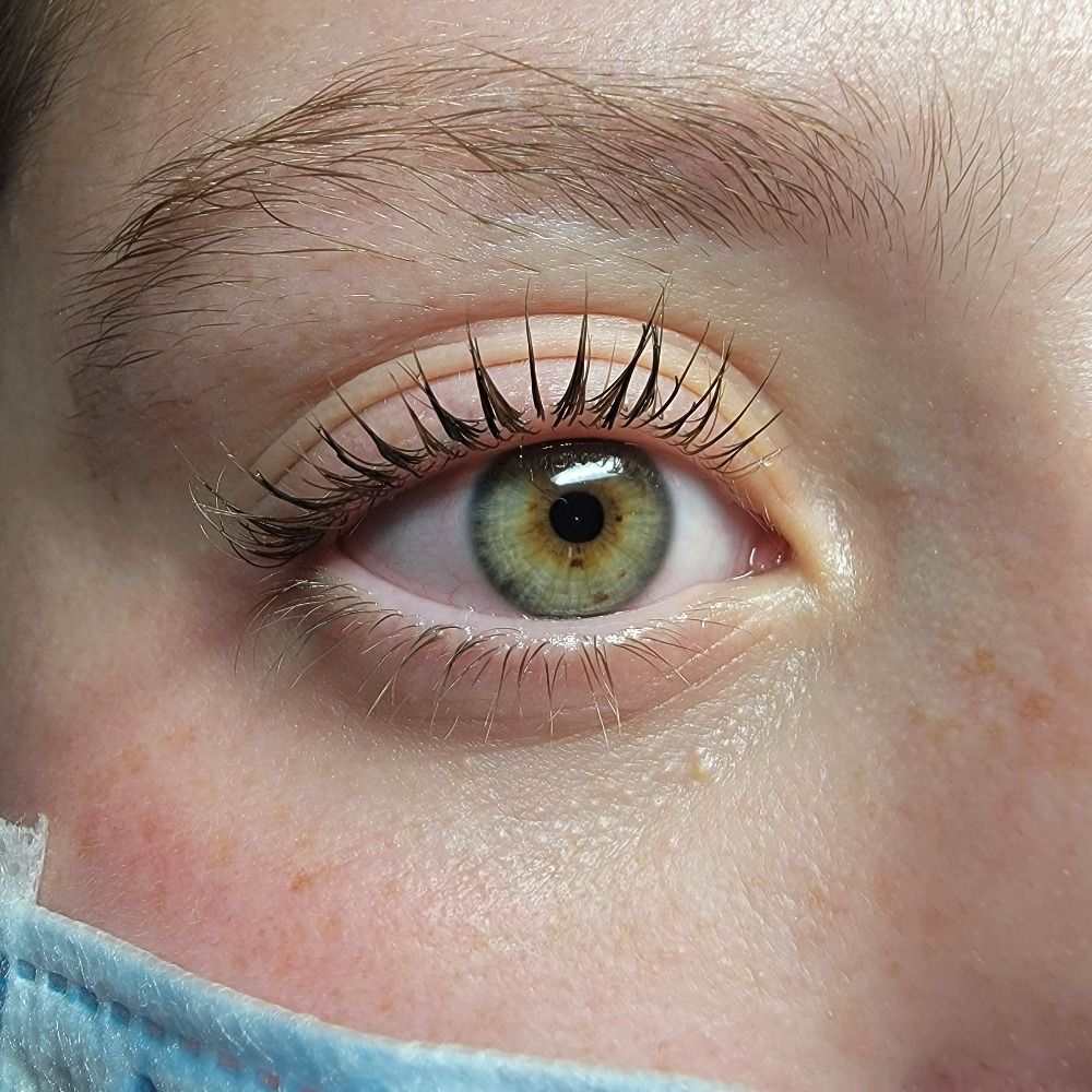 A close up of a woman 's green eye with mascara