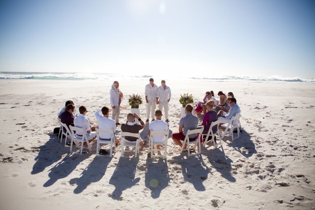 A group of people are sitting in a circle on the beach.