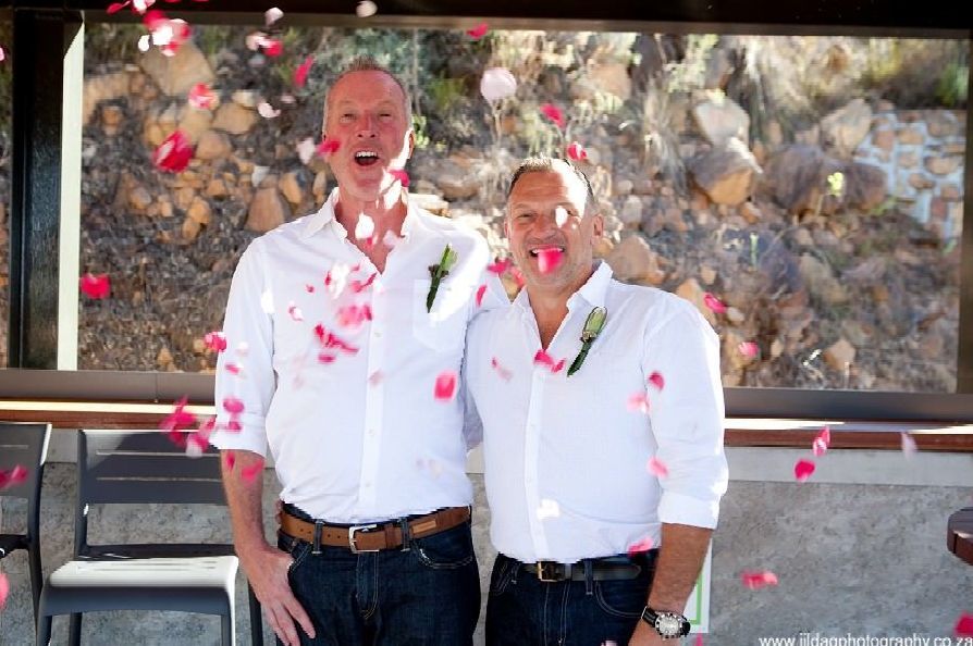 Two men are standing next to each other with confetti falling on them.