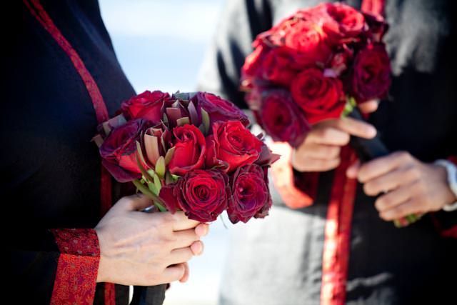 A bride and groom holding red roses in their hands