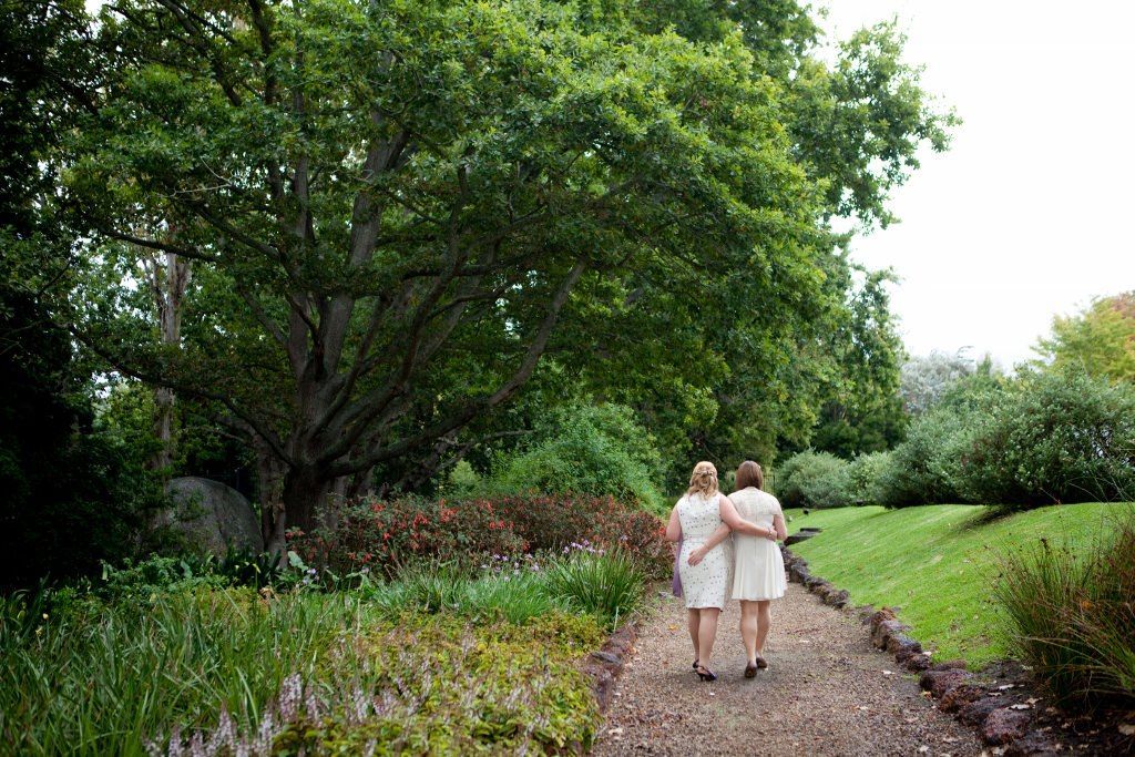 Two women are walking down a path in a park.