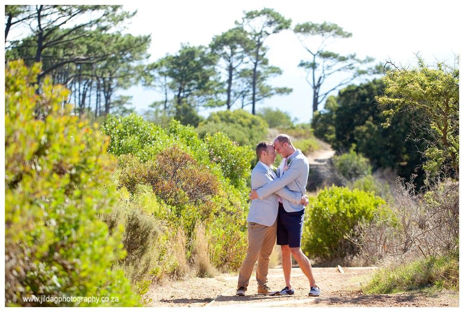 A man and a woman are hugging each other on a dirt path in the woods.