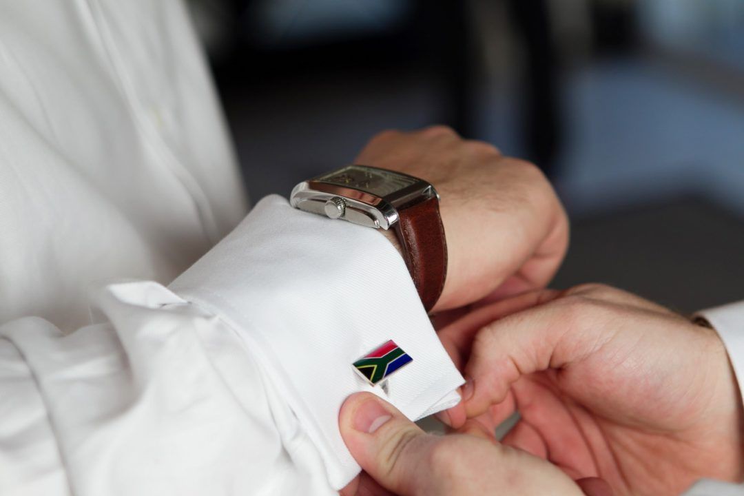 A man wearing a watch is adjusting his cufflinks