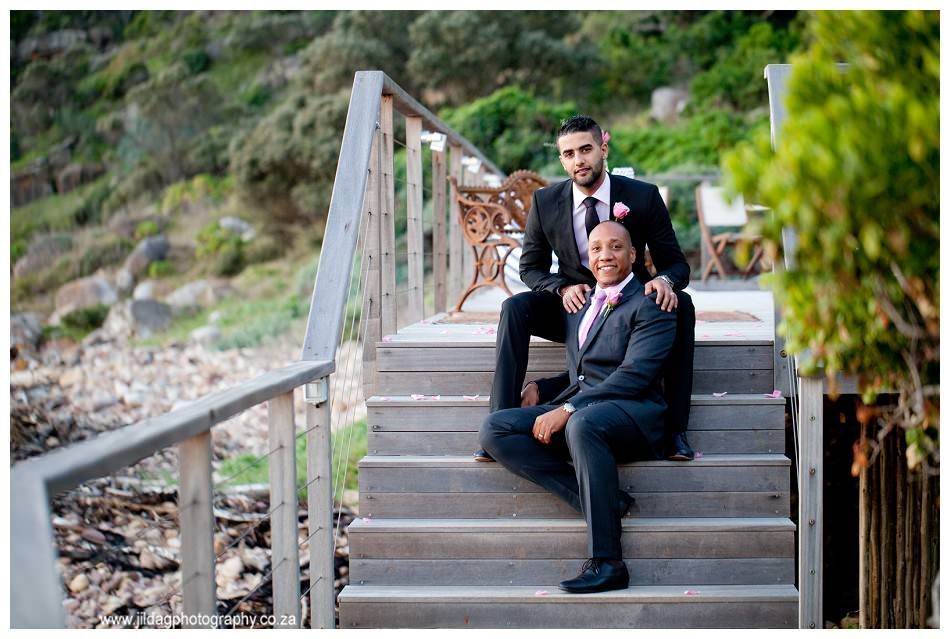 Two men in suits are sitting on a set of stairs.